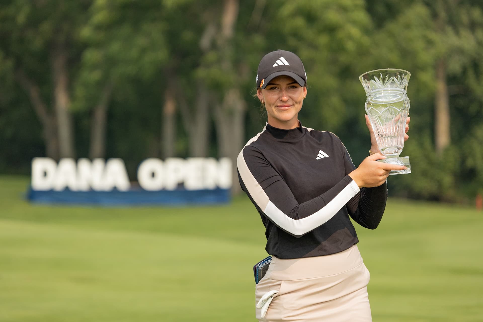 A golfer holds up the trophy on the course at the Dana Open.